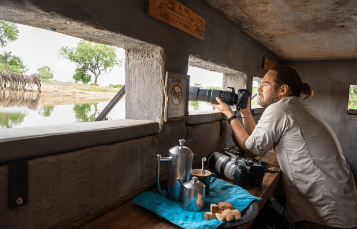 S006-IT2 -Photographer Standing at Window of a Small Kitchen Sustainable Safaris Africa - Journeys - Luxury Madikwe Family Safari - Photographer Standing at Window of a Small Kitchen