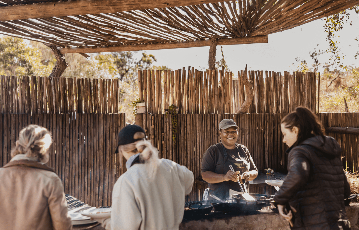 S002-IT2 - Guests Getting Served from Fire by Staff for Lunch Sustainable Safaris Africa - Journeys - Luxury Kruger Safari - Guests Getting Served from Fire by Staff for Lunch